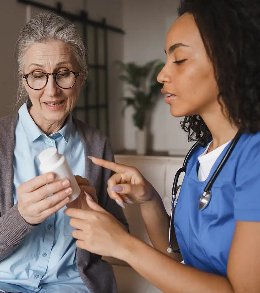 Nurse explaining care instructions to an older adult and a family caregiver at home.